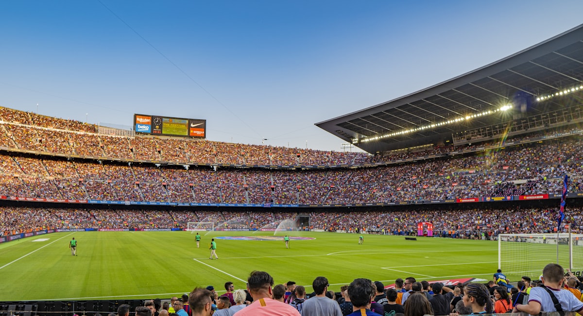 A match in progress, seen from the back of a full stand, with the pitch and the far stand below.